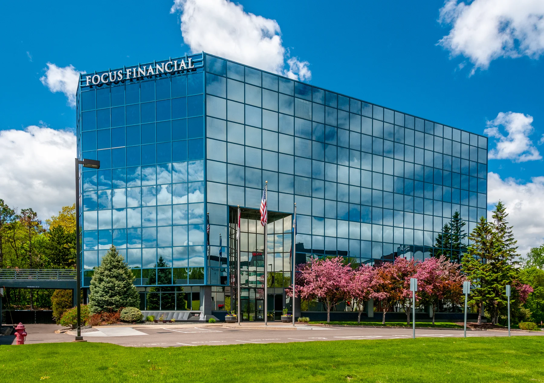 Glass office building at 1000 Shelard Parkway with flowering trees and a green lawn